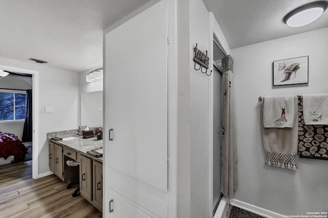 bathroom featuring vanity, a textured ceiling, hardwood / wood-style flooring, and curtained shower