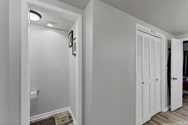 hallway with light hardwood / wood-style floors and a textured ceiling