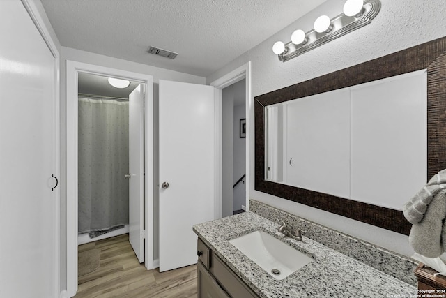 bathroom with hardwood / wood-style floors, vanity, a textured ceiling, and walk in shower