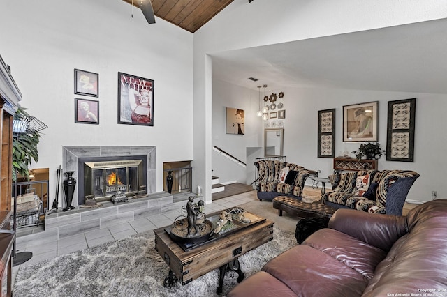 tiled living room with ceiling fan, a tiled fireplace, wood ceiling, and vaulted ceiling