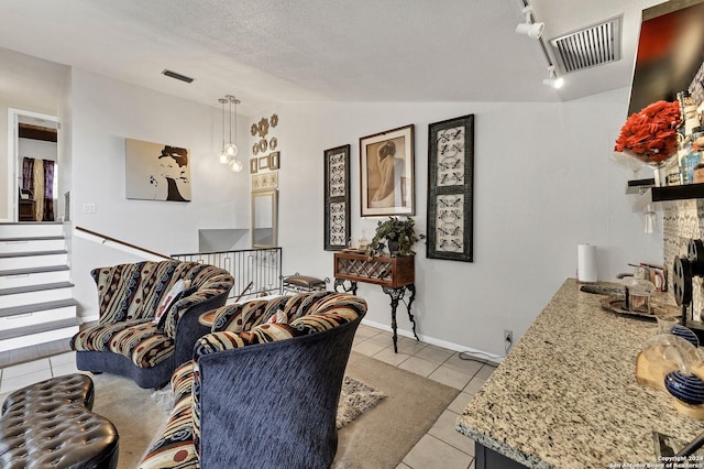 living room with rail lighting, vaulted ceiling, a textured ceiling, a fireplace, and light tile patterned floors