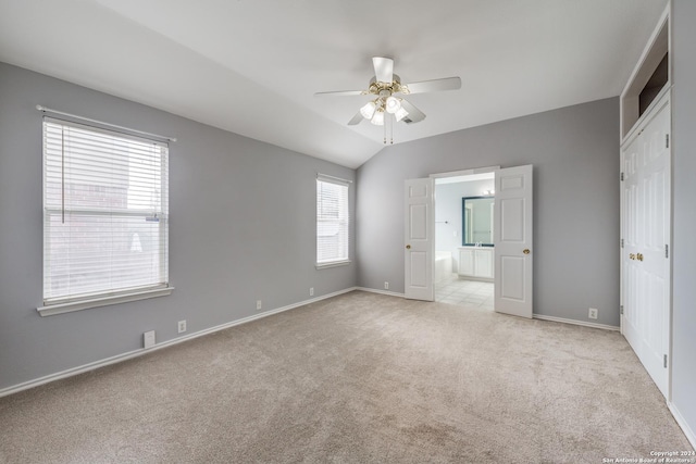 unfurnished bedroom with light carpet, connected bathroom, ceiling fan, and lofted ceiling