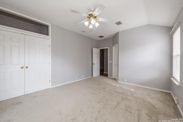 unfurnished bedroom with a closet, light colored carpet, ceiling fan, and lofted ceiling