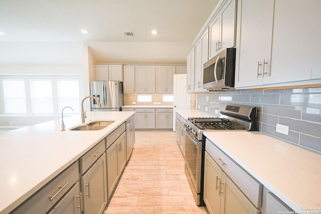 kitchen featuring gray cabinetry, sink, appliances with stainless steel finishes, and tasteful backsplash