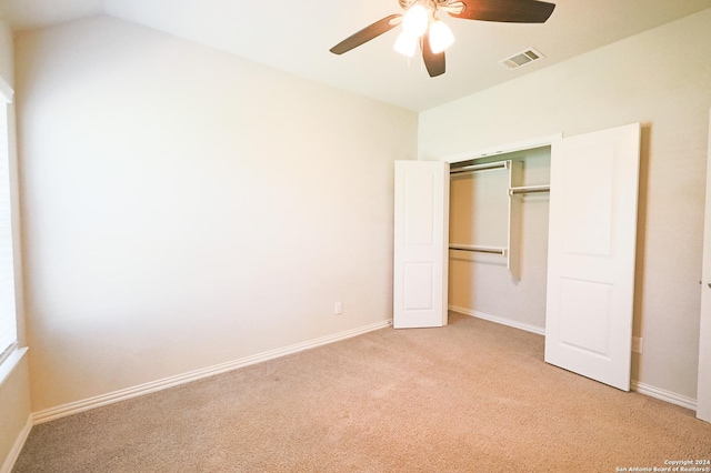 unfurnished bedroom featuring ceiling fan, lofted ceiling, light carpet, and a closet