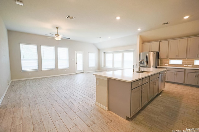 kitchen featuring sink, vaulted ceiling, ceiling fan, an island with sink, and appliances with stainless steel finishes