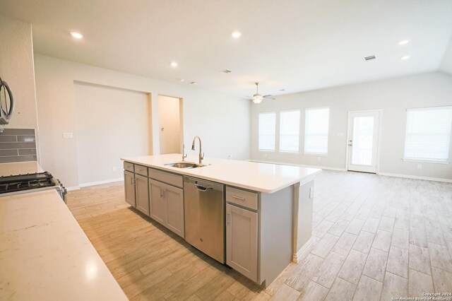 kitchen featuring gray cabinetry, ceiling fan, sink, stainless steel dishwasher, and a center island with sink