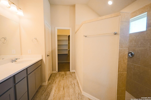 bathroom with hardwood / wood-style flooring, vanity, and tiled shower