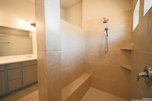 bathroom with hardwood / wood-style floors, vanity, and a tile shower