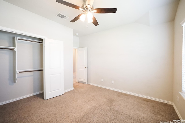 unfurnished bedroom featuring ceiling fan, light colored carpet, lofted ceiling, and a closet