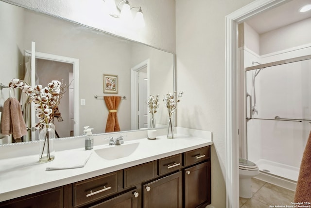 bathroom featuring tile patterned floors, vanity, toilet, and a shower with shower door