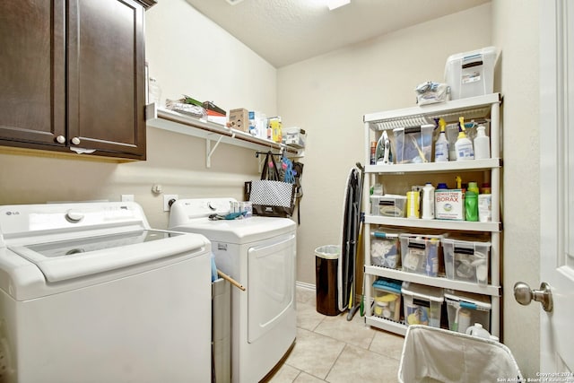 laundry room with washing machine and dryer, light tile patterned floors, cabinets, and a textured ceiling