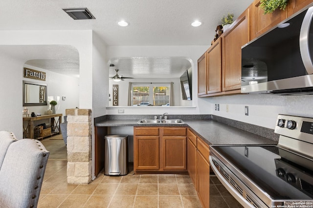 kitchen with a textured ceiling, stainless steel appliances, ceiling fan, and sink