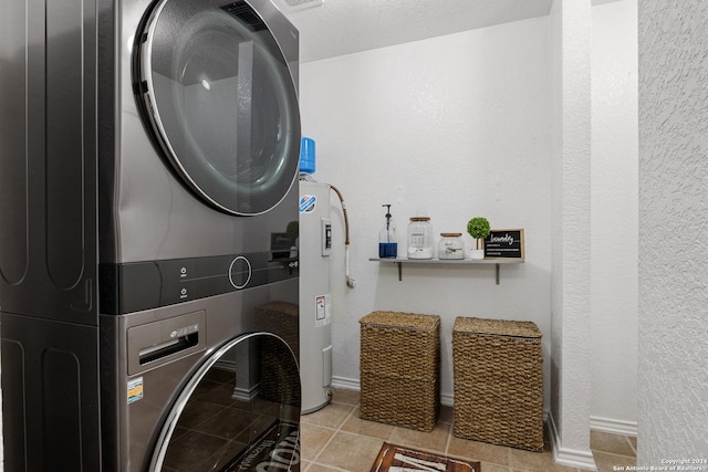 clothes washing area with light tile patterned flooring, electric water heater, and stacked washer and dryer