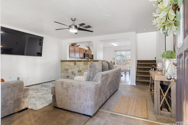 living room with ceiling fan and a textured ceiling