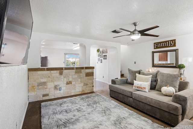 living room featuring ceiling fan and a textured ceiling