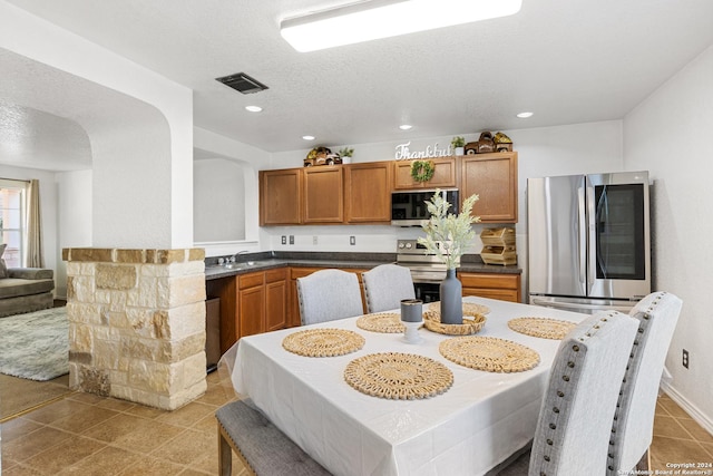 tiled dining room featuring a textured ceiling and sink