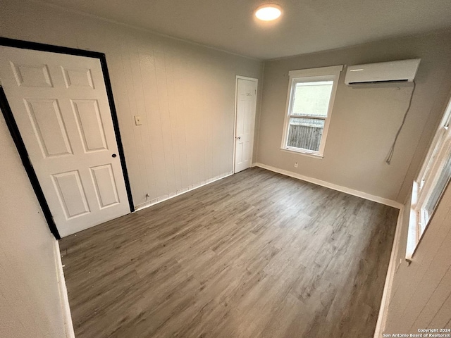 spare room with an AC wall unit and dark wood-type flooring