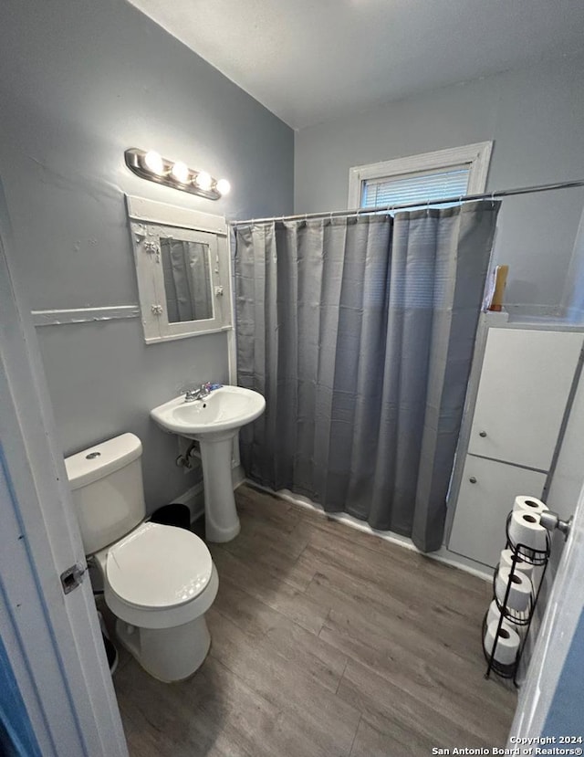 bathroom with a shower with shower curtain, hardwood / wood-style flooring, toilet, and sink