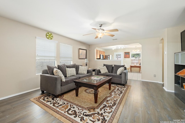 living room featuring dark hardwood / wood-style flooring, plenty of natural light, and ceiling fan with notable chandelier