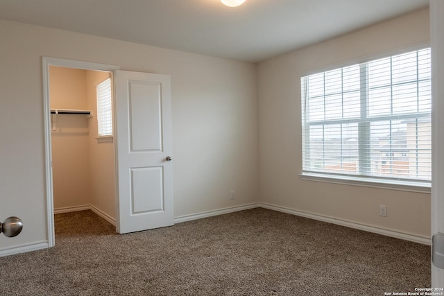 unfurnished bedroom featuring carpet, a spacious closet, and a closet