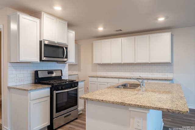 kitchen featuring white cabinets, stainless steel appliances, a kitchen island with sink, and sink