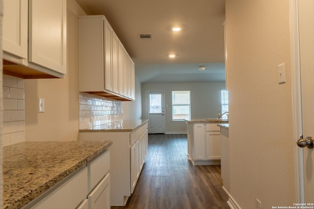 kitchen with backsplash, dark hardwood / wood-style floors, white cabinetry, and light stone counters