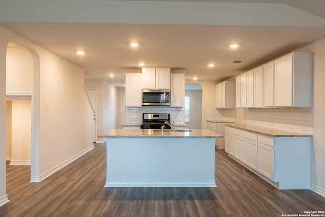 kitchen with tasteful backsplash, light stone countertops, white cabinets, and stainless steel appliances