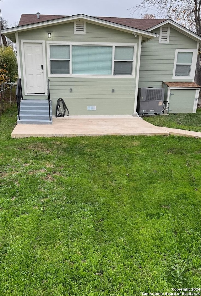 rear view of property featuring a patio area, a yard, and cooling unit