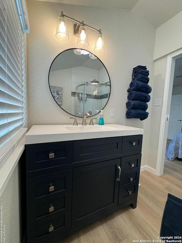 bathroom featuring vanity, a shower with shower door, vaulted ceiling, and hardwood / wood-style flooring