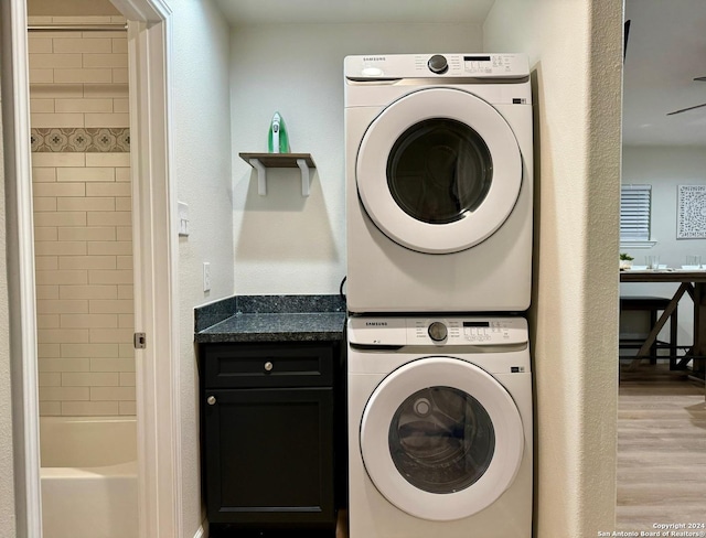 laundry room with light hardwood / wood-style floors and stacked washer and clothes dryer