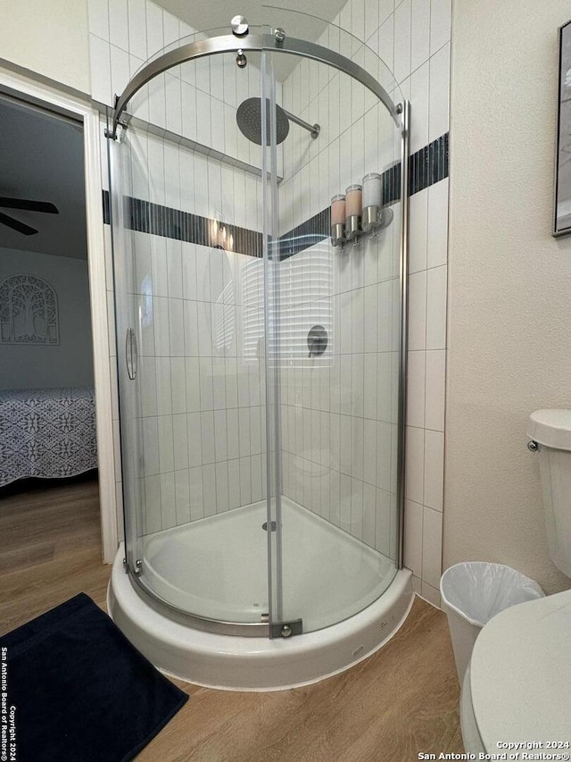 bathroom with toilet, a shower with shower door, and wood-type flooring