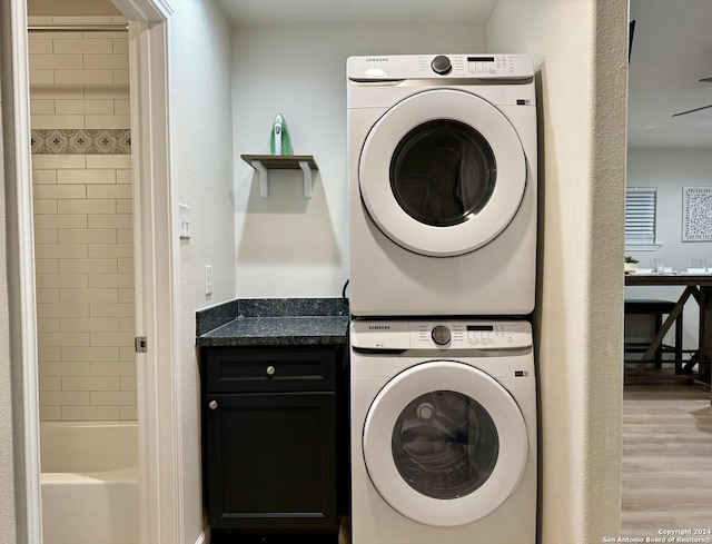 washroom featuring light hardwood / wood-style floors and stacked washer / drying machine