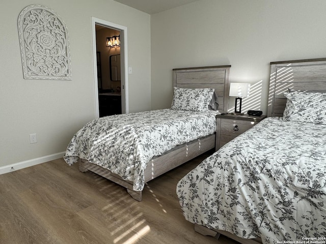 bedroom featuring ensuite bathroom and dark hardwood / wood-style floors