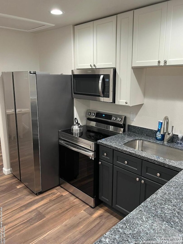 kitchen with white cabinets, sink, stainless steel appliances, and hardwood / wood-style floors