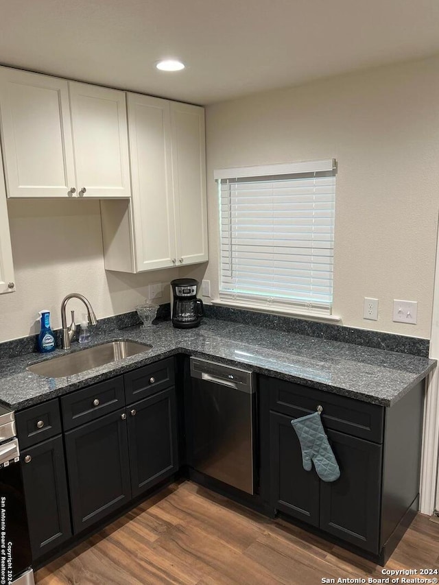 kitchen with white cabinetry, dishwasher, sink, dark stone countertops, and wood-type flooring