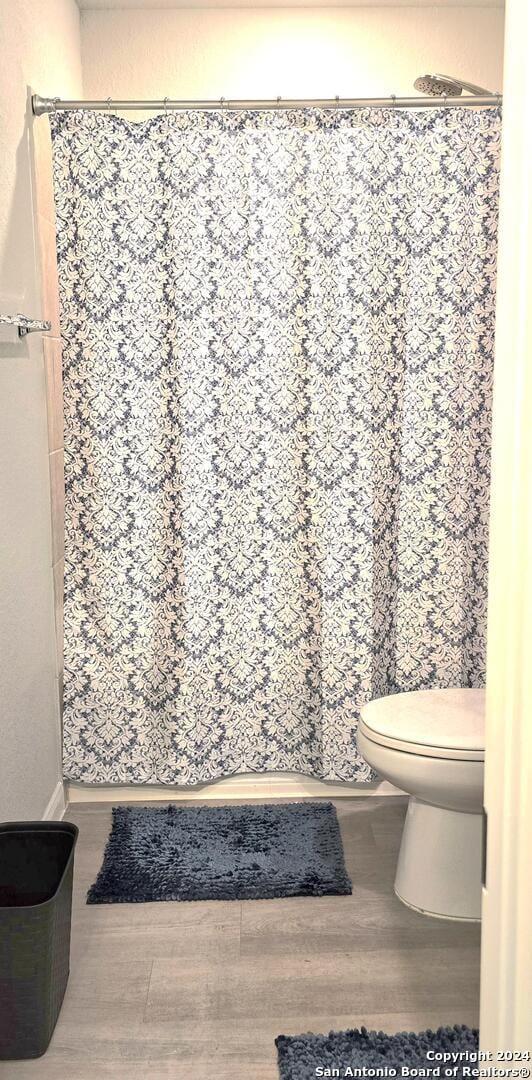 bathroom featuring hardwood / wood-style floors, a shower with curtain, and toilet