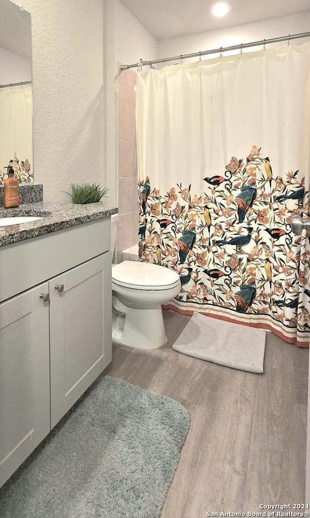 bathroom featuring hardwood / wood-style flooring, vanity, toilet, and walk in shower