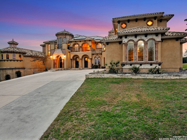 mediterranean / spanish-style home with a balcony and a yard