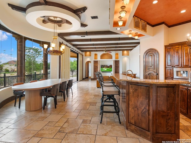 kitchen with a chandelier, beam ceiling, pendant lighting, and a healthy amount of sunlight