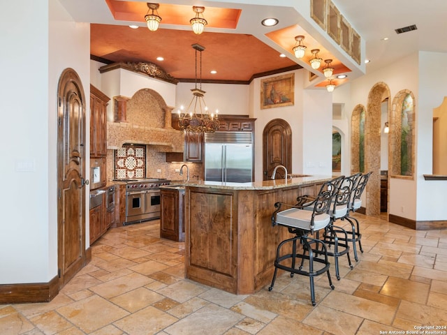 kitchen featuring light stone countertops, hanging light fixtures, kitchen peninsula, a breakfast bar area, and high end appliances