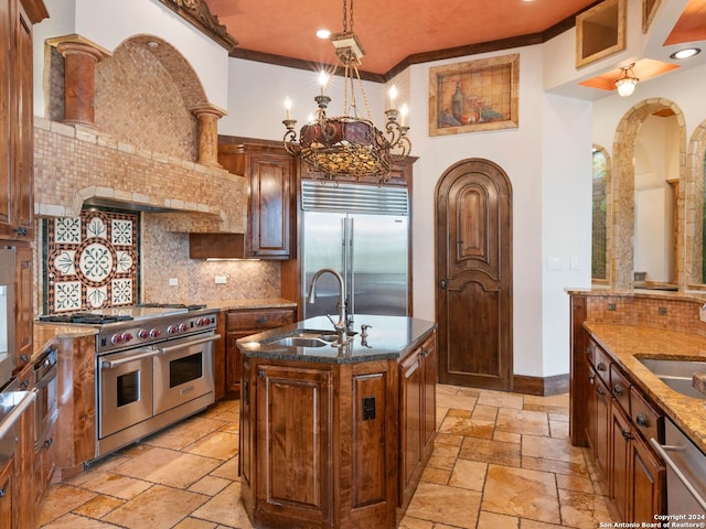 kitchen with sink, backsplash, crown molding, an island with sink, and high end appliances