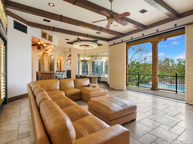 living room featuring beamed ceiling, ceiling fan with notable chandelier, and a healthy amount of sunlight