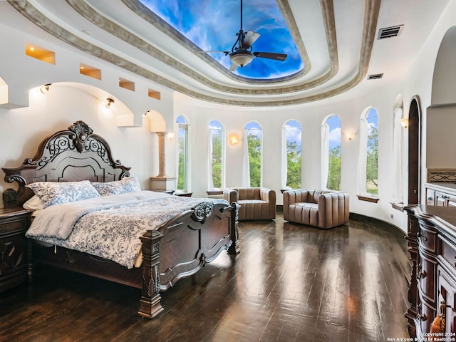 bedroom with ceiling fan, dark hardwood / wood-style floors, and a tray ceiling