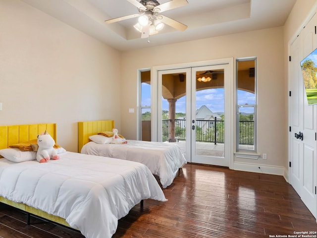 bedroom featuring a tray ceiling, access to exterior, ceiling fan, and dark hardwood / wood-style flooring