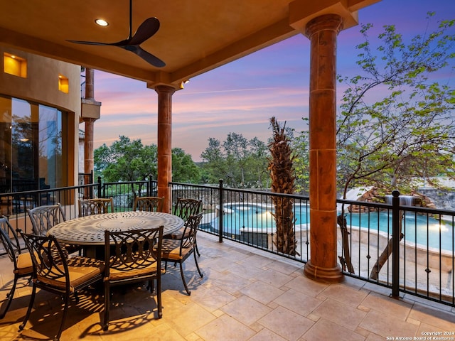 patio terrace at dusk featuring ceiling fan and a community pool