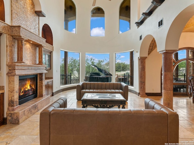 living room with a premium fireplace, a high ceiling, and decorative columns