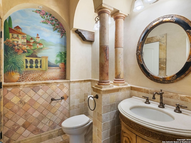 bathroom with vanity, tile walls, and toilet