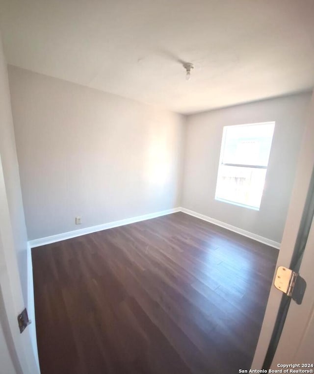 unfurnished room with dark wood-type flooring