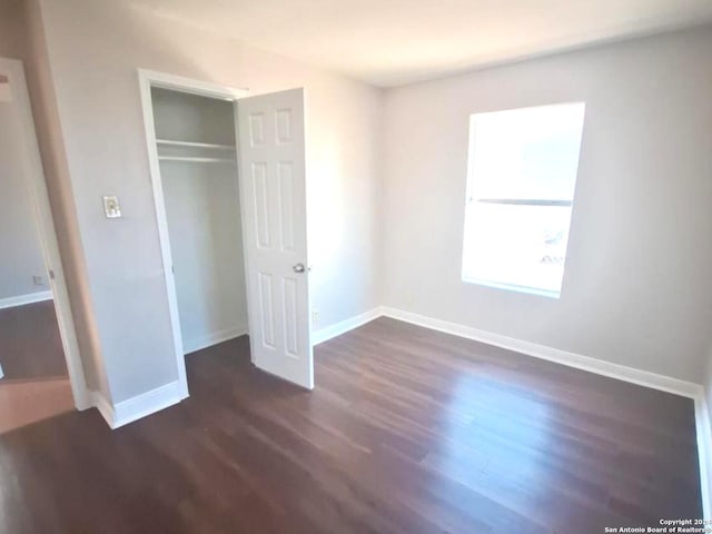 unfurnished bedroom featuring dark hardwood / wood-style floors and a closet